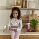 Kislány uzsonnás dobozzal és a Little Dutch Fairy wonders szívószálas kulaccsal a konyhapulton