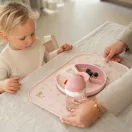 Kislány eszik a családi asztalnál Little Dutch Fairy Garden tányéralátéten lévő osztott tányérból