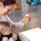 Baba és szülő közösen nézik a Petit Boum Gold szenzoros palackot fényasztal felett