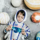 Astronauta jelmezbe öltözött kisfiú játszik a Petit Boum Universe érzékelő palackkal