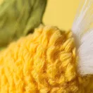 Közeli kép a Jellycat kukorica plüss puha sárga anyagáról és fehér bojtjáról