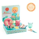A Djeco Dishware kit fa evőeszközei, műanyag poharai és tányérjai a csepegtetőként használható dobozon