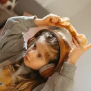 Kislány fején a Kidywolf Kidyears oroszlános fejhallgató miközben felhelyezi a mágneses fület