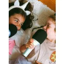 Két kislány fekve énekel a Kidywolf Kidymic karaoke mikrofonokba a gyerekszobában