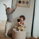 Ket kisgyerek enekel es konfettit szor a Kidywolf rozsaszin karaoke mikrofonnal a szobaban