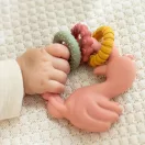 Kisbaba keze fogja a Little Dutch flamingó formájú szilikon rágókát egy puha kötött takarón