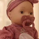 Little Dutch Livia itatós-pisilős baba virágmintás rózsaszín pamutruhában és fejpánttal