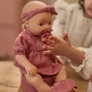 Little Dutch Livia itatós-pisilős baba virágmintás rózsaszín pamutruhában és fejpánttal