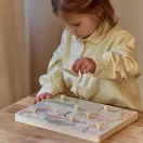 Kisgyermek egy fa asztalnál a Little Dutch Safari Friends hangos puzzle játék közben