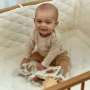Kisbaba játszik a kiságyban a nyitott Little Dutch Safari Friends textil könyvvel